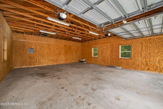 garage featuring electric panel, wooden walls, and a garage door opener