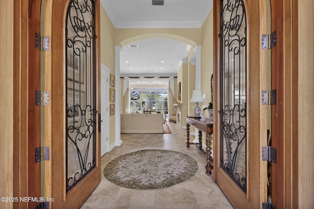 entryway with light tile patterned floors and ornamental molding