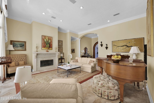 living room with decorative columns, a textured ceiling, and crown molding