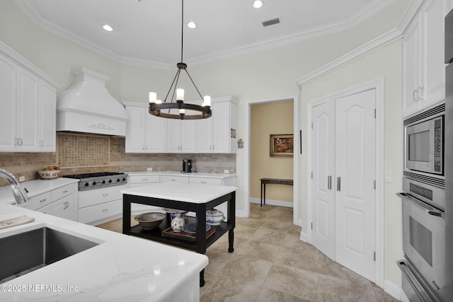 kitchen with decorative light fixtures, custom exhaust hood, white cabinetry, ornamental molding, and stainless steel appliances