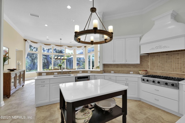 kitchen with decorative light fixtures, decorative backsplash, an inviting chandelier, stainless steel gas cooktop, and custom range hood