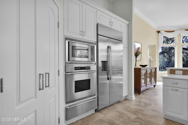 kitchen with ornamental molding, white cabinets, and built in appliances