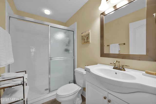 bathroom featuring toilet, vanity, a shower with door, and a textured ceiling