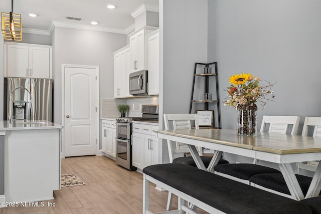 234 Thistleton Way, Saint Augustine, FL 32092 - kitchen featuring stainless steel appliances, ornamental molding, light wood-style floors, backsplash, and white cabinets