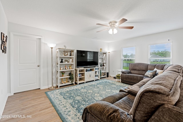 living room with ceiling fan, light hardwood / wood-style floors, and a textured ceiling