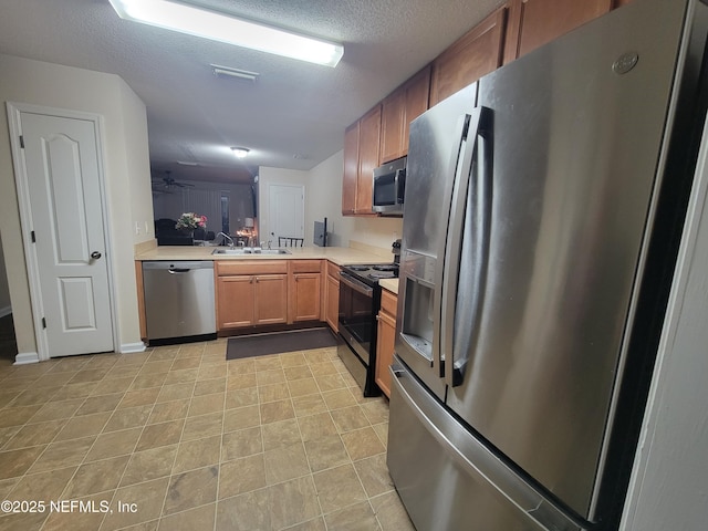 kitchen with sink, stainless steel appliances, kitchen peninsula, and a textured ceiling