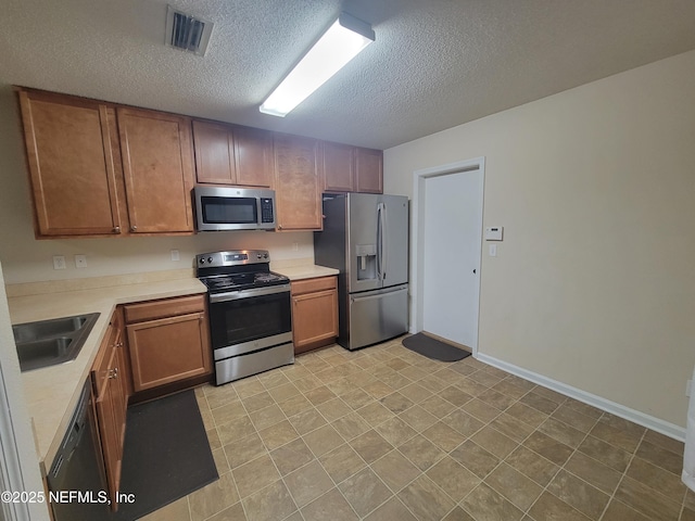 kitchen with appliances with stainless steel finishes, sink, and a textured ceiling