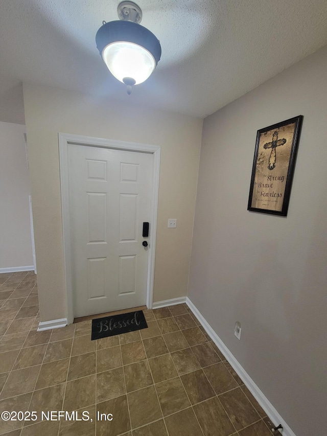 foyer entrance featuring dark tile patterned flooring and a textured ceiling