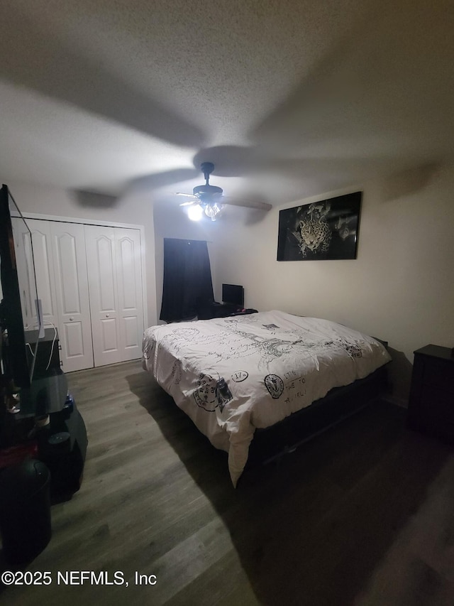 bedroom featuring ceiling fan, a closet, wood-type flooring, and a textured ceiling