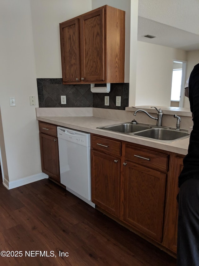 kitchen with tasteful backsplash, dishwasher, dark wood-type flooring, and sink