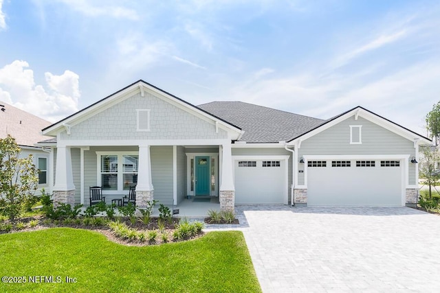 craftsman house with covered porch, a front yard, and a garage