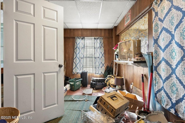 misc room with a paneled ceiling and wooden walls