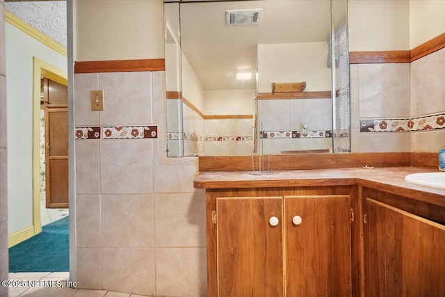 bathroom with tile patterned floors, vanity, and tile walls