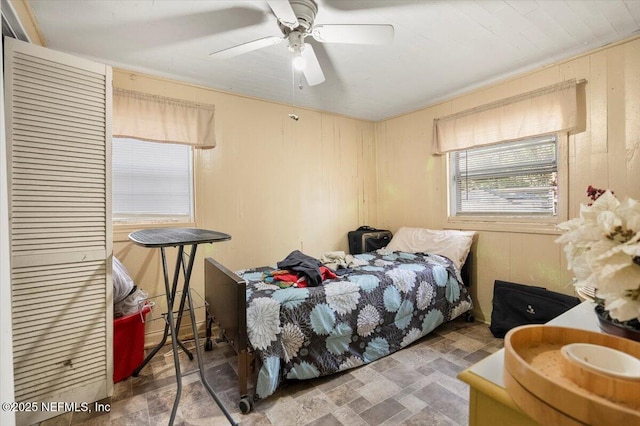 bedroom featuring ceiling fan and wood walls