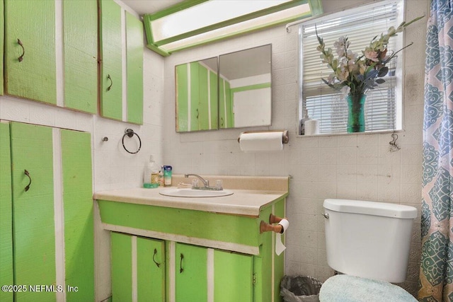 bathroom with vanity, toilet, and tile walls