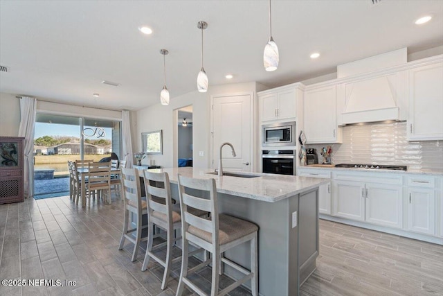 kitchen featuring sink, stainless steel appliances, premium range hood, and white cabinetry