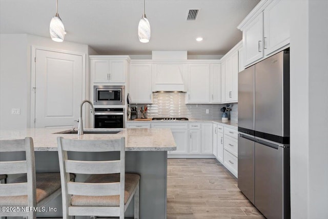 kitchen with stainless steel appliances, white cabinets, backsplash, and hanging light fixtures