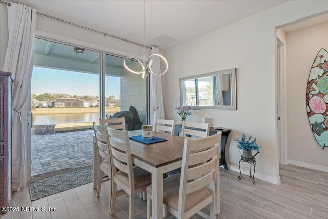 dining space with light hardwood / wood-style floors and a water view