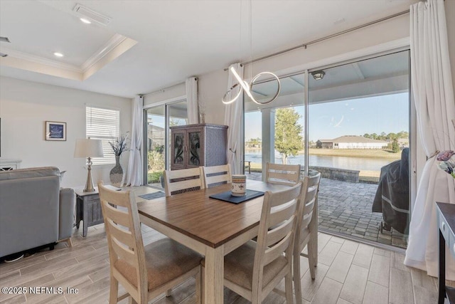 dining area featuring a water view, crown molding, and a tray ceiling