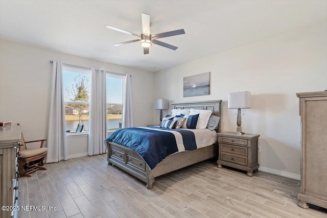 bedroom featuring ceiling fan, light hardwood / wood-style floors, and a water view