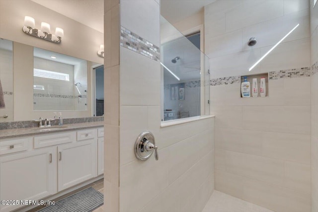 bathroom with a tile shower and vanity