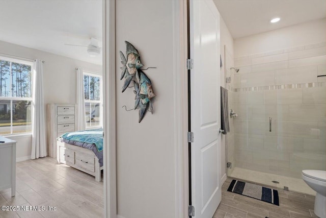 bathroom featuring ceiling fan, a shower with door, and toilet