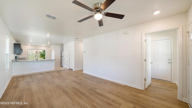 unfurnished living room featuring ceiling fan, light hardwood / wood-style flooring, and sink