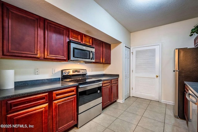 kitchen with stainless steel appliances, light tile patterned flooring, and a textured ceiling