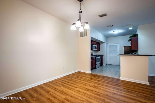 kitchen featuring stainless steel appliances, light wood-type flooring, a chandelier, and pendant lighting