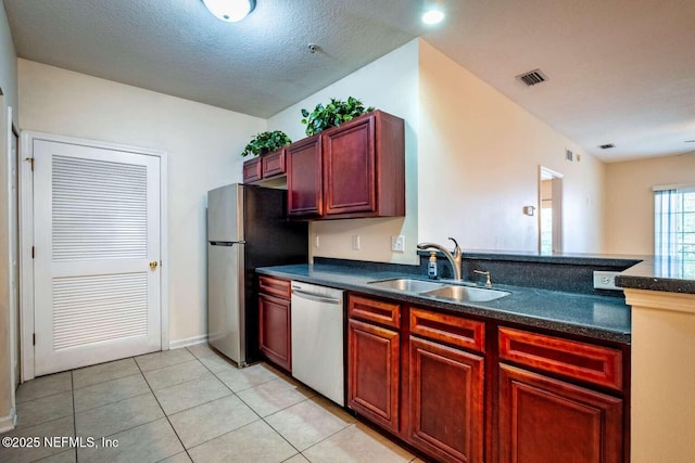 kitchen featuring a textured ceiling, appliances with stainless steel finishes, light tile patterned floors, and sink