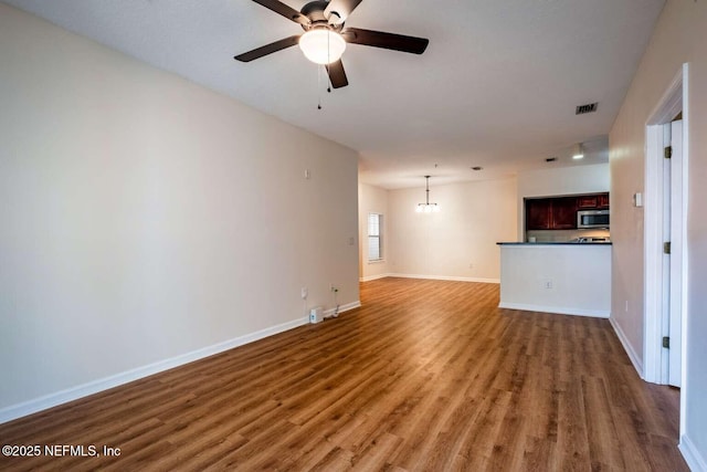 unfurnished living room with ceiling fan with notable chandelier and dark hardwood / wood-style floors