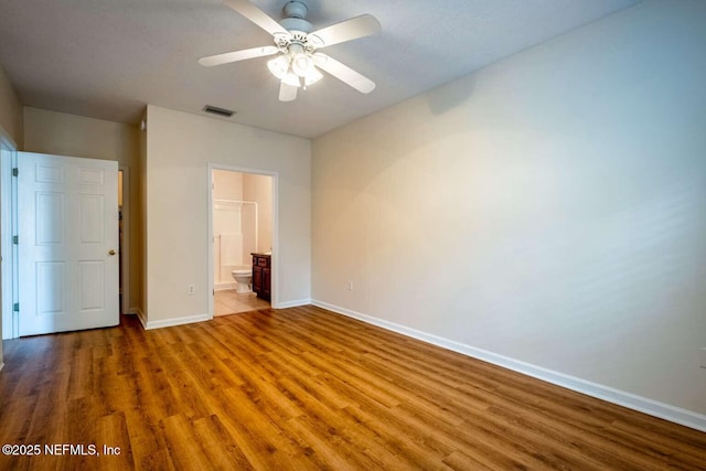 unfurnished bedroom with ensuite bathroom, ceiling fan, and hardwood / wood-style floors