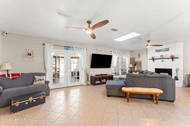 living room with a textured ceiling, light tile patterned floors, a skylight, and french doors