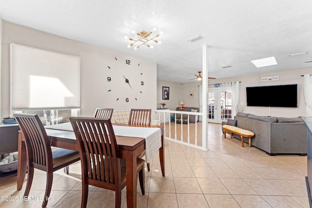 dining area with light tile patterned floors, french doors, ceiling fan with notable chandelier, and a textured ceiling