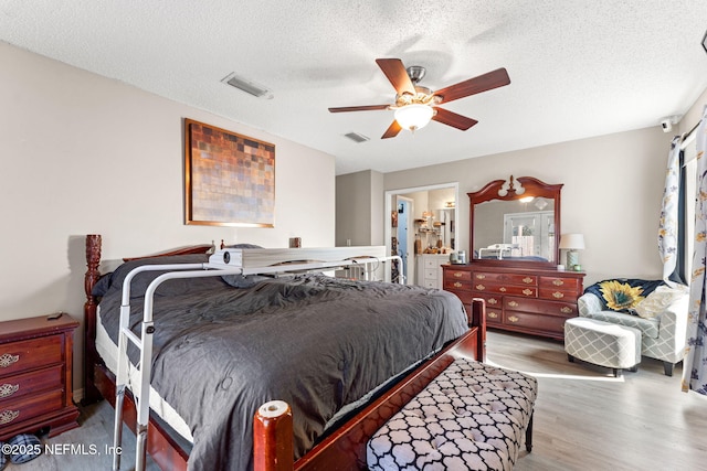 bedroom featuring ceiling fan, connected bathroom, a textured ceiling, and light wood-type flooring