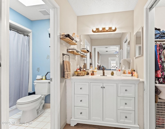 bathroom with curtained shower, a textured ceiling, tile patterned flooring, vanity, and toilet