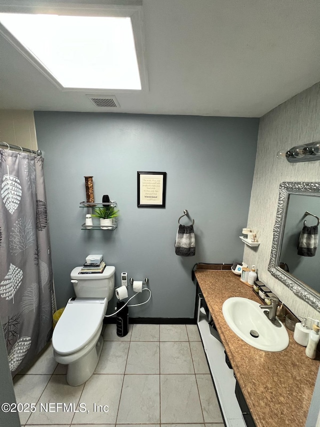 bathroom with toilet, vanity, and tile patterned flooring