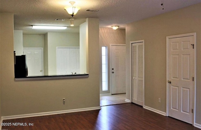 foyer entrance with dark hardwood / wood-style flooring and a textured ceiling