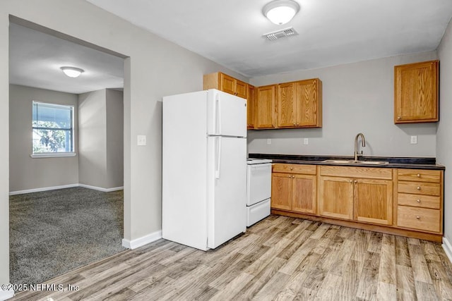 kitchen with light carpet, stove, white fridge, and sink