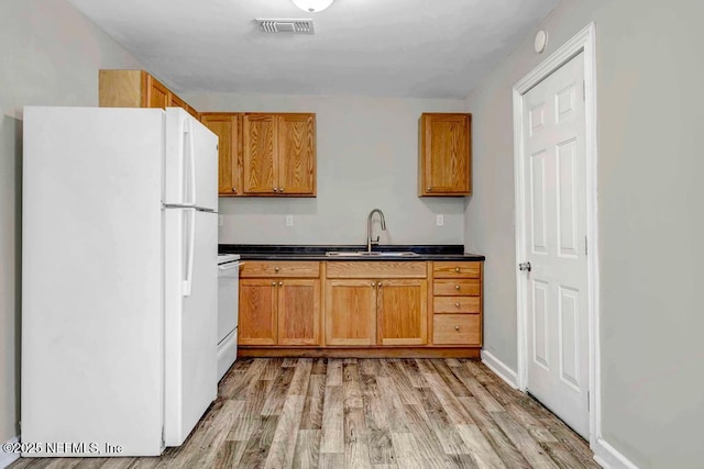 kitchen with stove, white fridge, light hardwood / wood-style floors, and sink