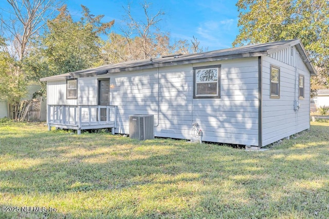 rear view of property with central air condition unit, a wooden deck, and a yard