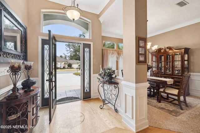 entrance foyer with ornamental molding and light hardwood / wood-style flooring