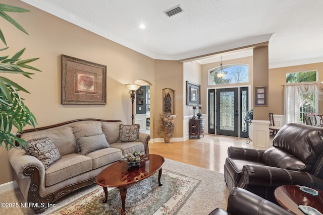 living room featuring crown molding, light hardwood / wood-style flooring, and a textured ceiling