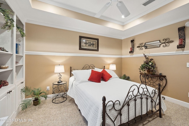 bedroom with ceiling fan, ornamental molding, a tray ceiling, and carpet floors