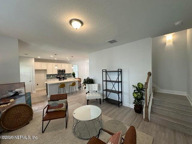 living room featuring a textured ceiling and light hardwood / wood-style floors