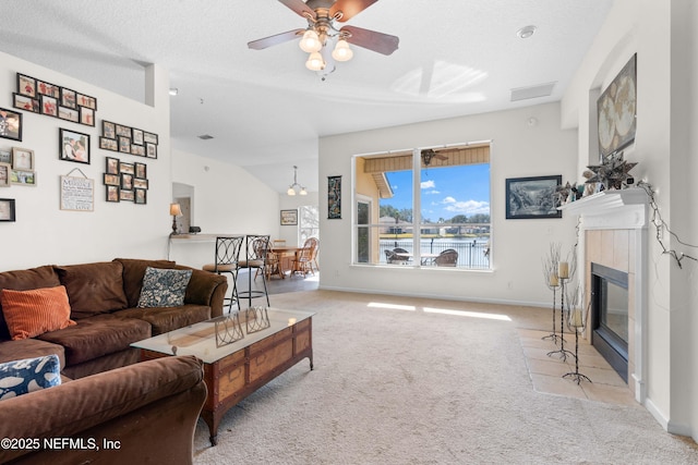 living room with light colored carpet, visible vents, a tiled fireplace, a ceiling fan, and baseboards