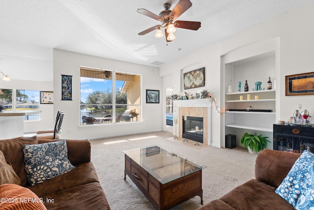 living room with a textured ceiling, carpet, a tile fireplace, and a healthy amount of sunlight