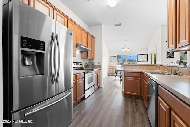 kitchen featuring brown cabinets, visible vents, appliances with stainless steel finishes, a sink, and under cabinet range hood