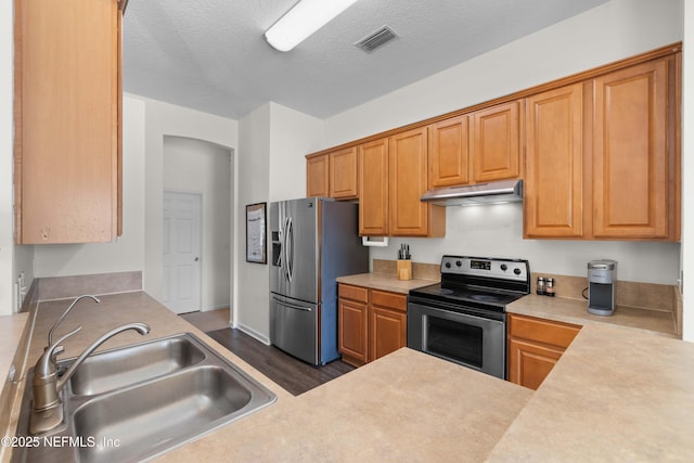 kitchen with visible vents, light countertops, appliances with stainless steel finishes, a sink, and under cabinet range hood