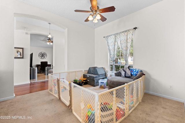 interior space with baseboards, a ceiling fan, and light colored carpet